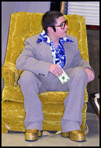 1970s Character sits in gold chair.